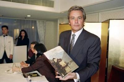 French actor Alain Delon shows off a copy of "Importants Tableaux Modernes", a book of  paintings he had collected, during a visit to Tokyo in 1990